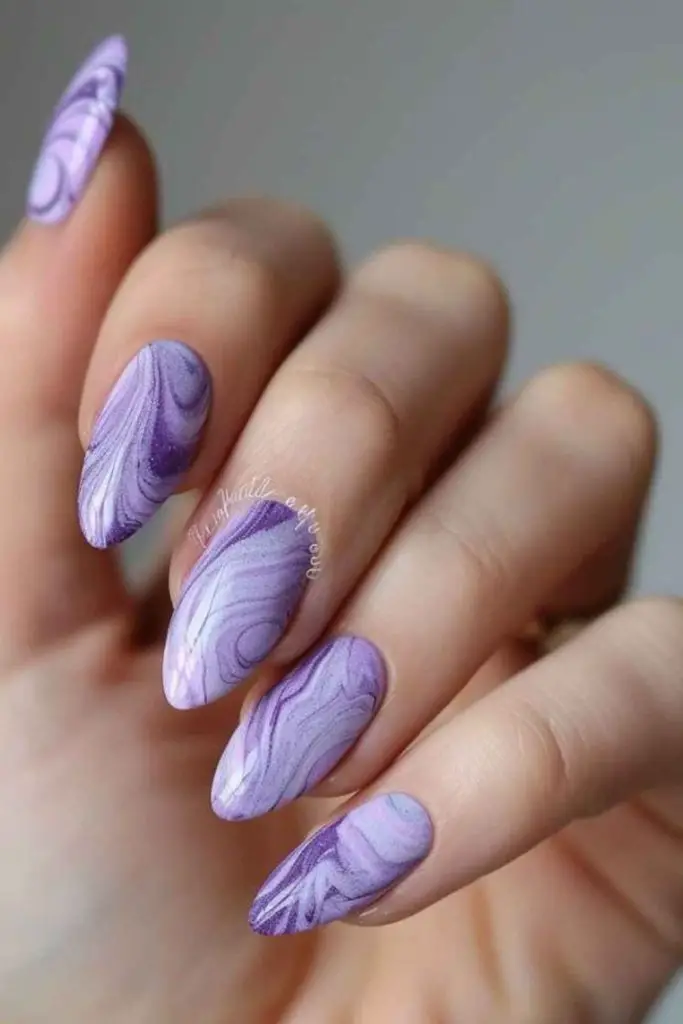 Purple nails with glittery swirling designs.