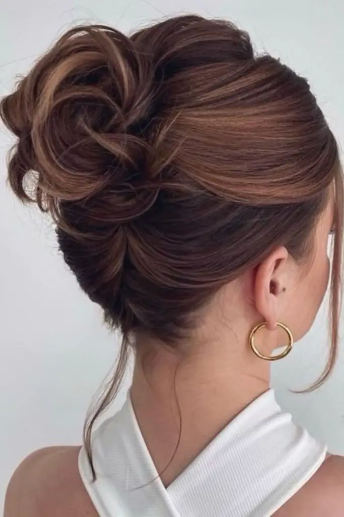 Teased chignon with loose, soft tendrils.