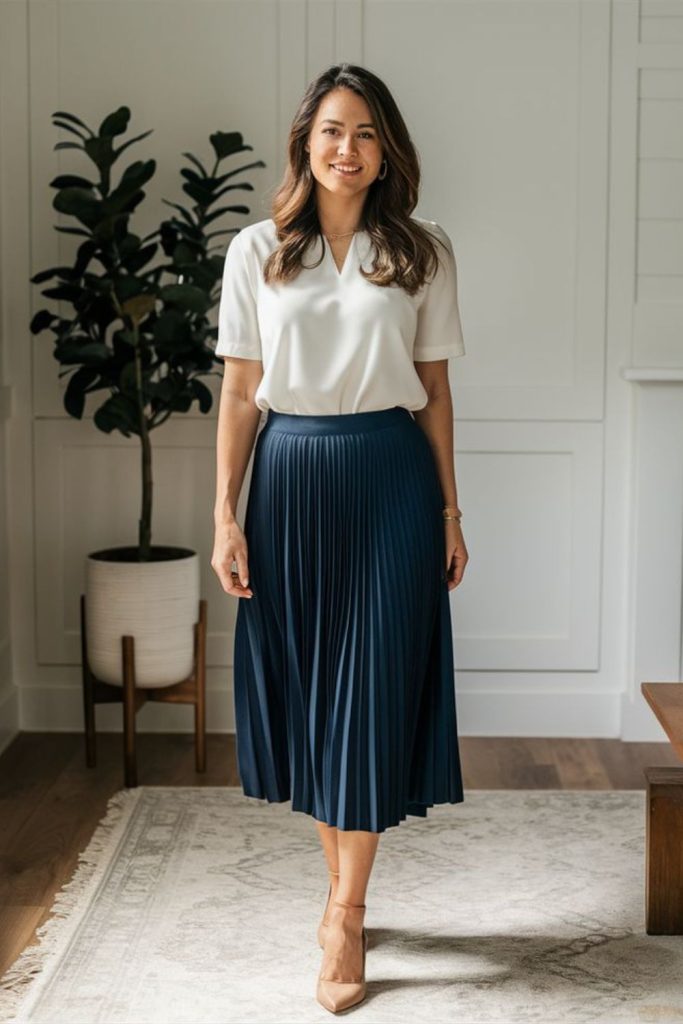 White blouse with navy pleated skirt.