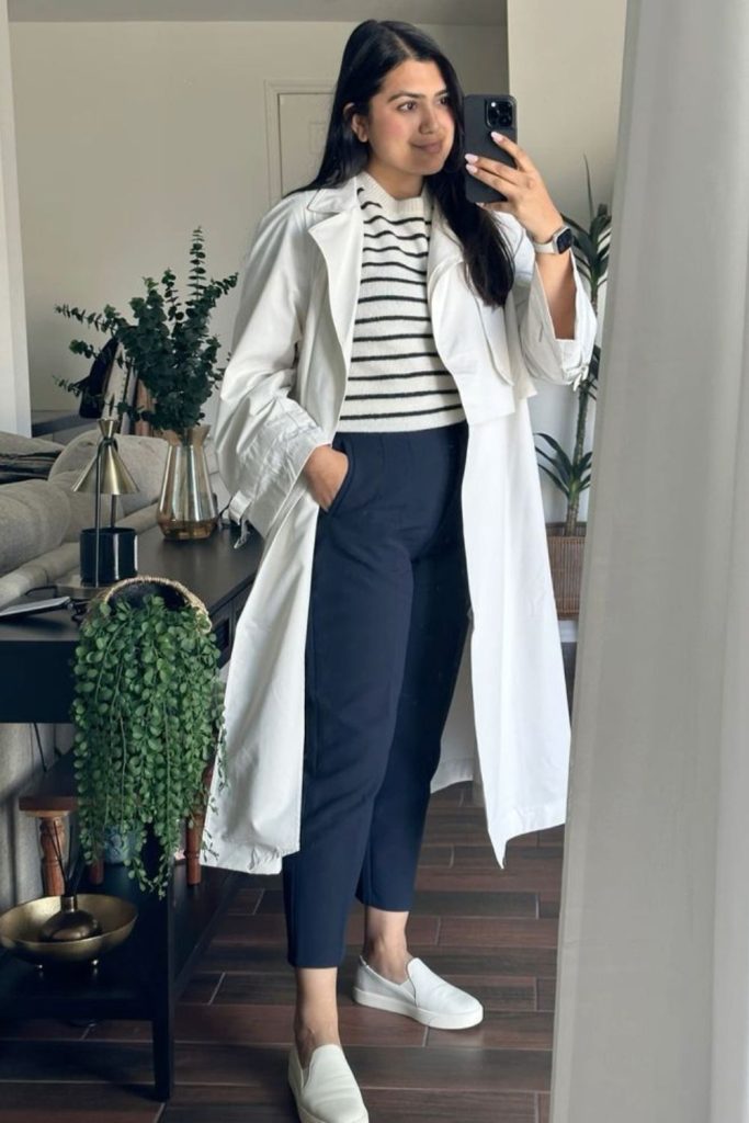 Off-white trench over navy trousers.