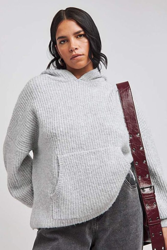 Grey knitted hoodie with dark jeans.