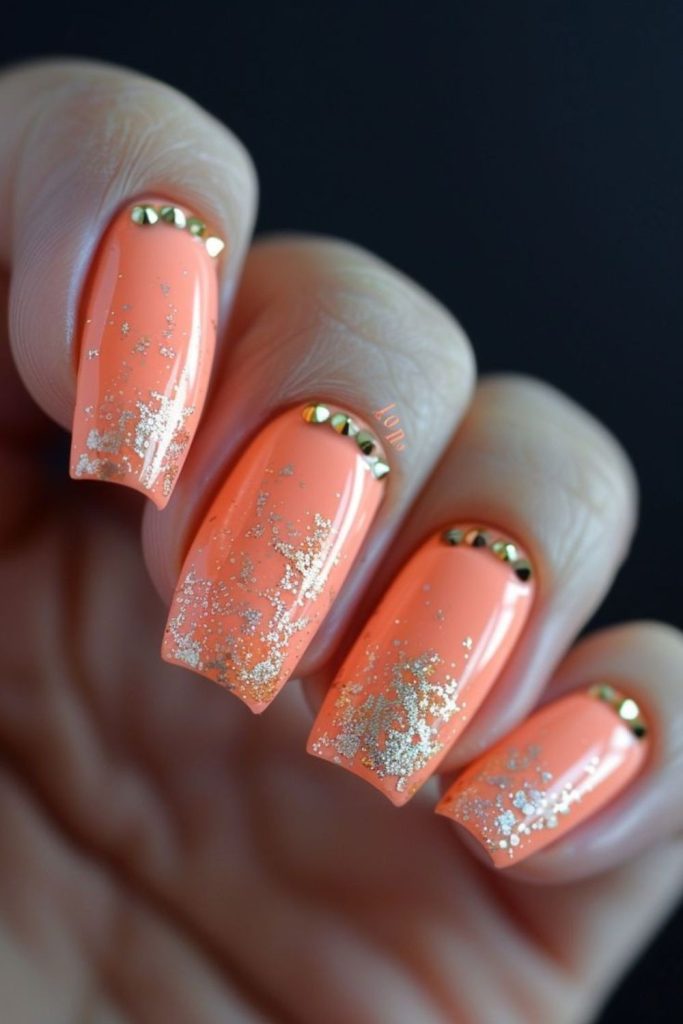 Vibrant coral nails with playful shimmer.