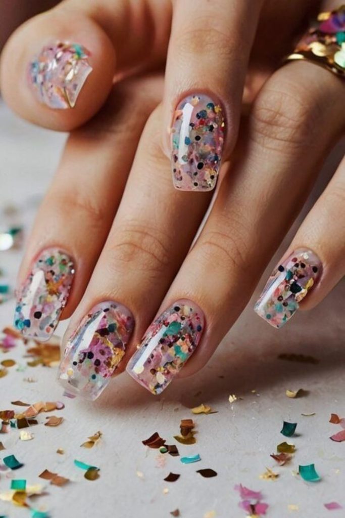 Icy blue nails with scattered metallic confetti.