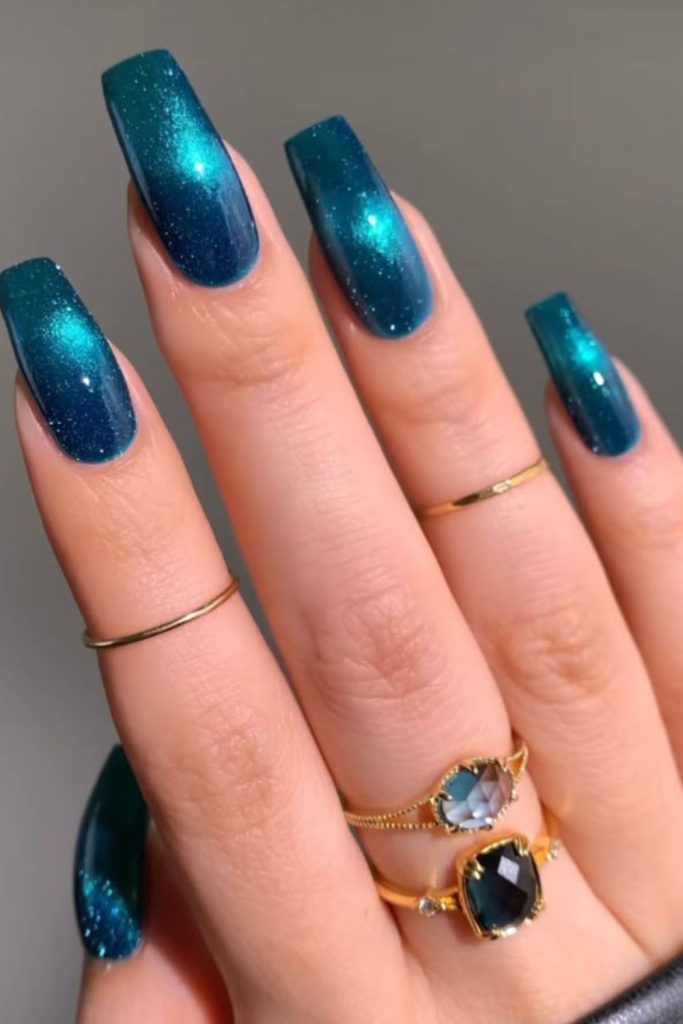 Swirled navy teal nails with silver glitter.