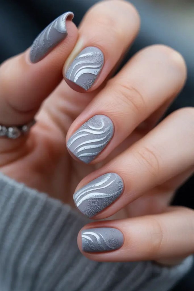 Grey nails with flowing angular patterns.