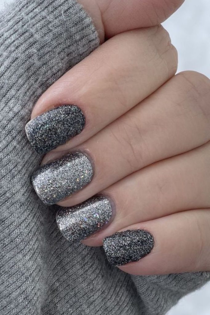 Grey translucent nails with scattered holographic shards.
