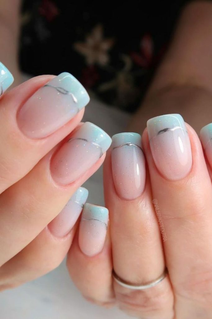 Aqua blue arcs on nude nails.