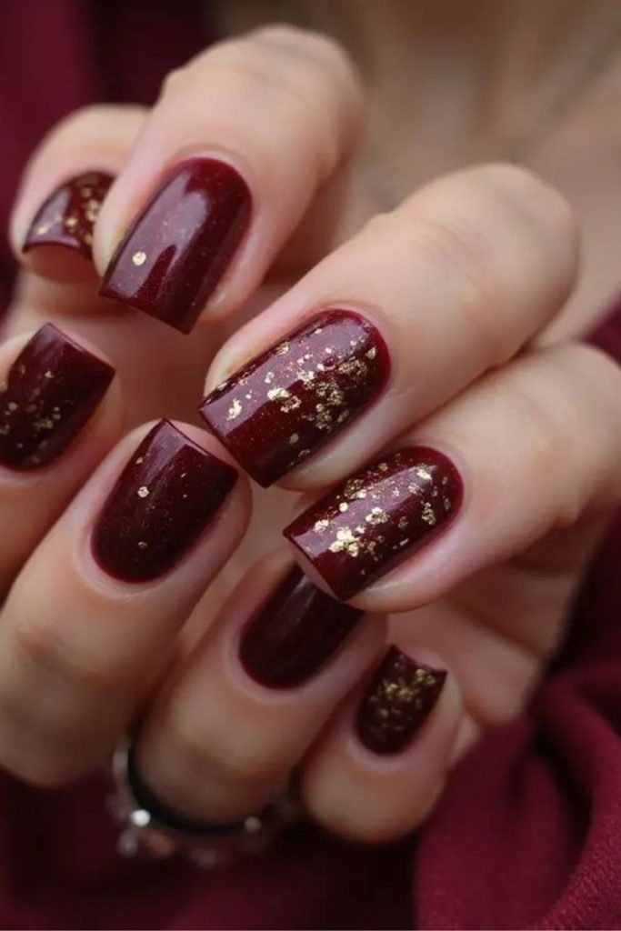 Deep ruby nails with rose gold sparkles.