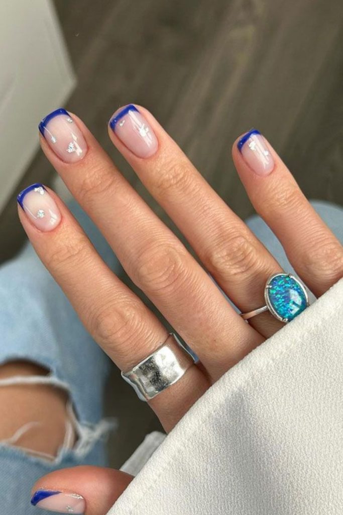 Deep blue tips over cream nails.