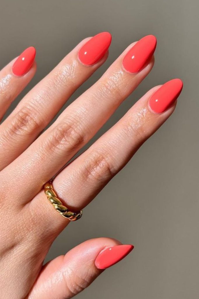 Coral glossy nails, ocean-inspired brightness.