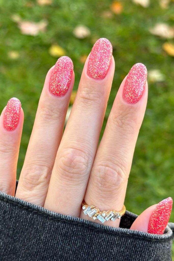 Vibrant coral nails with reflective glitter