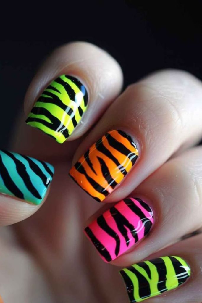 Neon zebra nails with bold stripes.