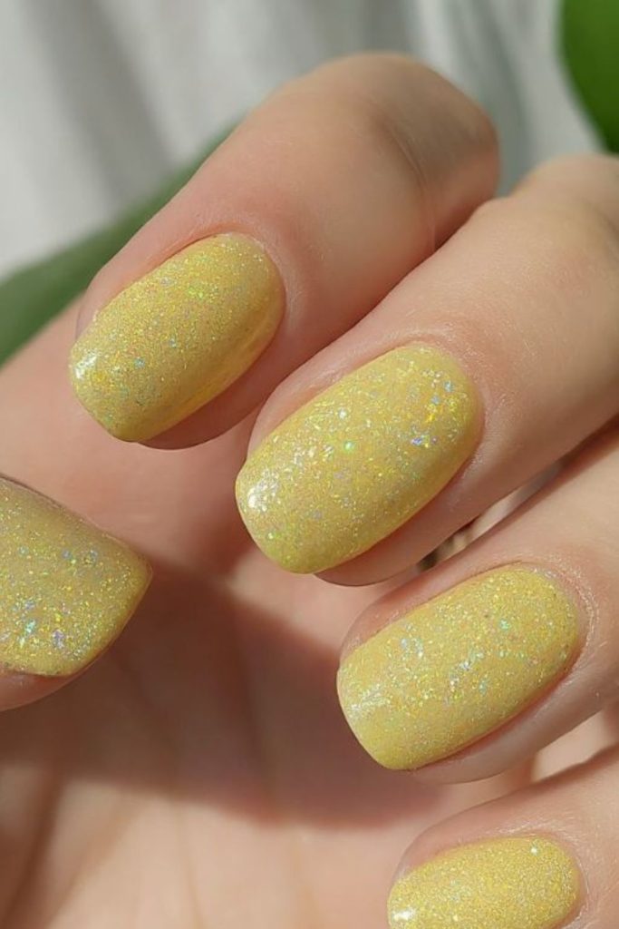 Pale yellow nails with sparkling accents.