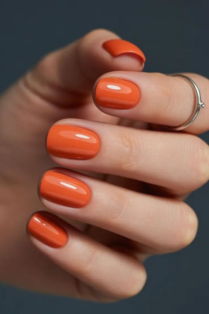 Vibrant orange glossy nails, playful energy.