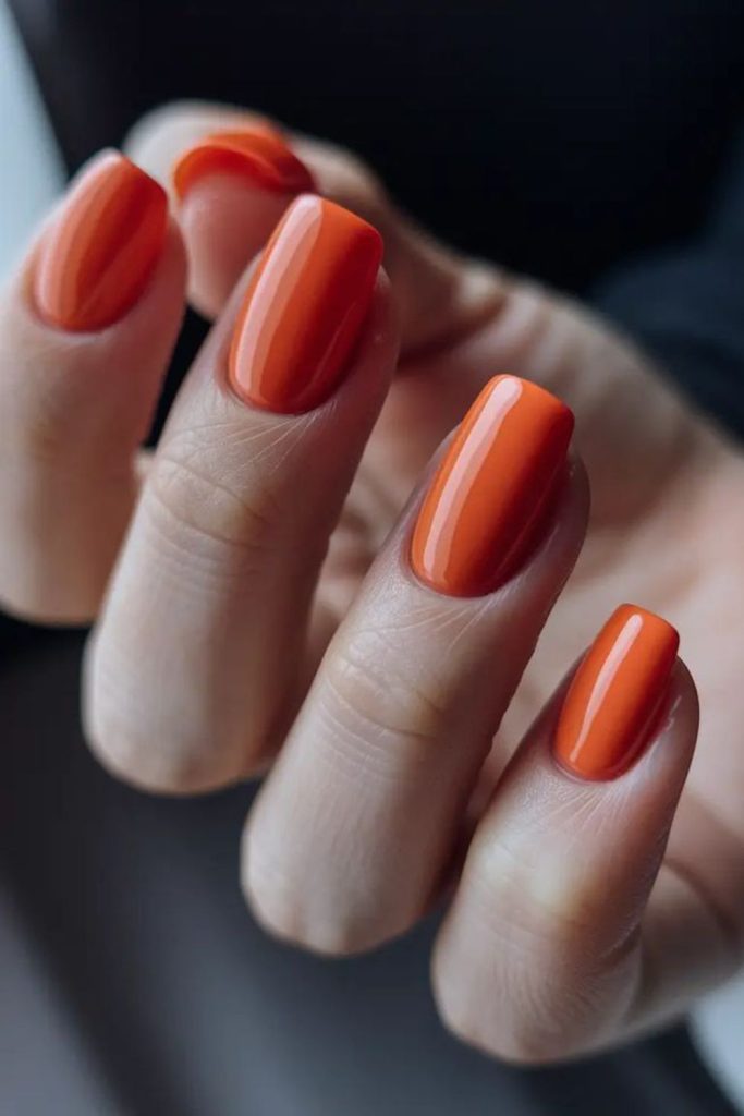 Bright orange nails, vibrant energetic flair.