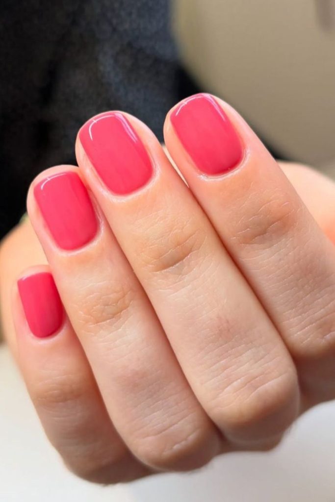 Bright watermelon pink nails with sparkle.