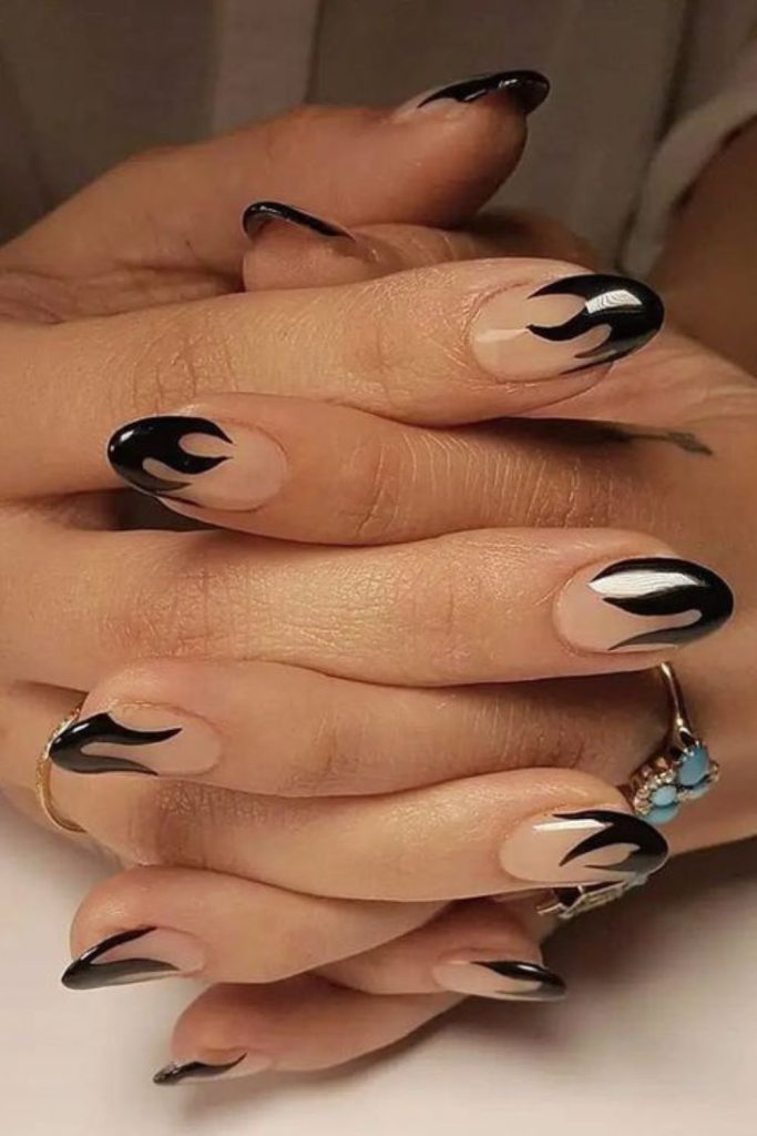 Black glossy flames on nude nails.