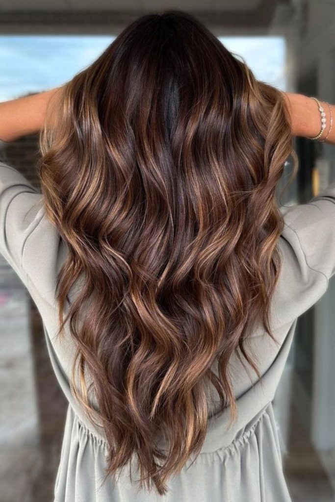 Honey swirls in chestnut brown hair waves.