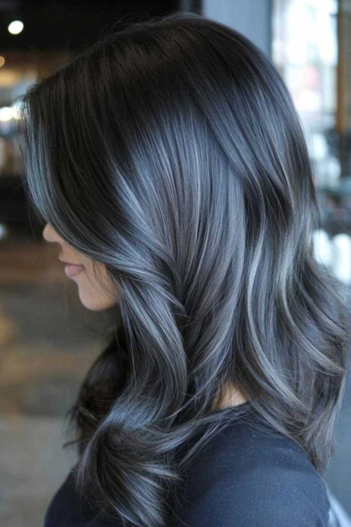 Subtle ash blonde streaks dark hair.