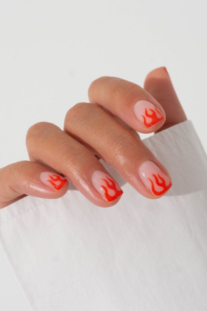 Minimal flames on nude nail tips.
