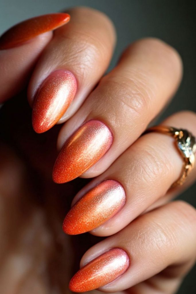 Glowing citrus orange nails with gold flecks.