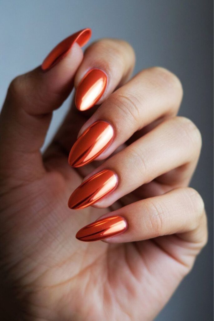 Chrome orange mirror effect metallic nails.