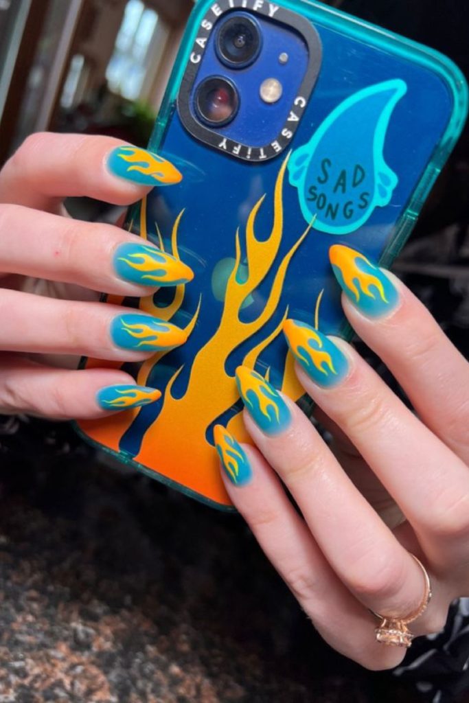 Blue nails with yellow flame swirl accents.