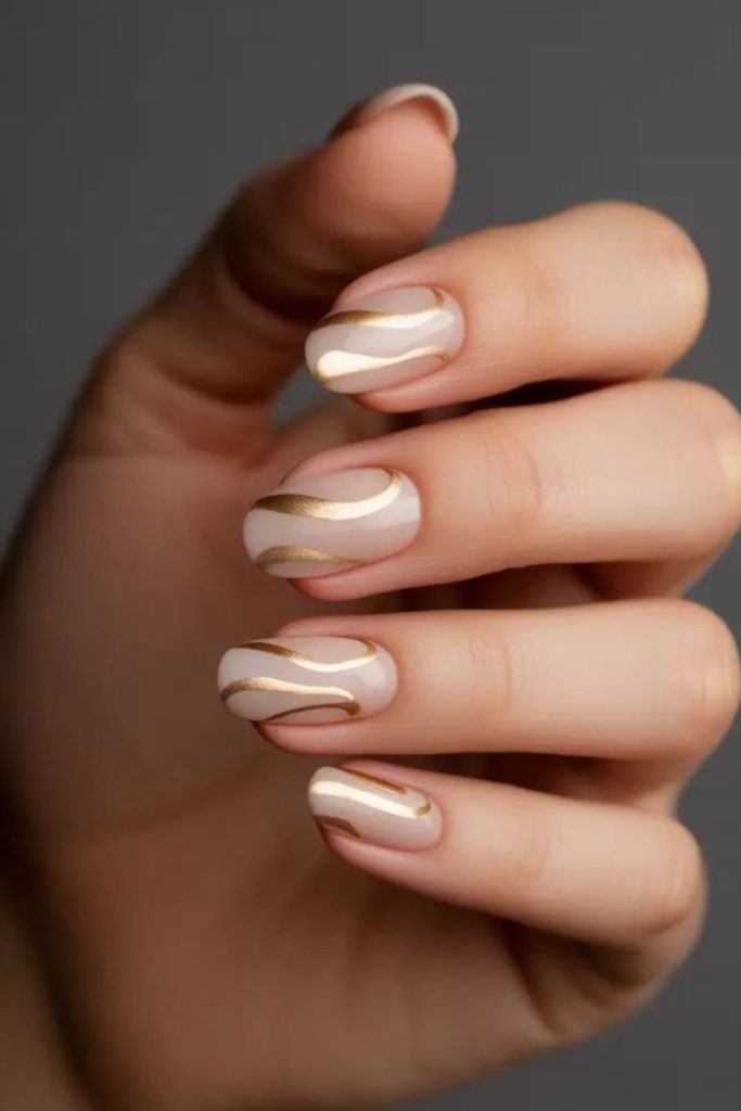 Nude nails with gold ribbon accents.