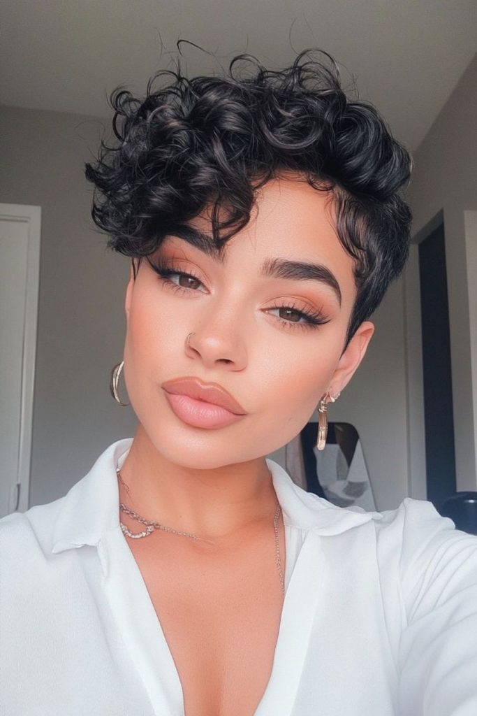 Short curly pixie haircut with bold volume and playful natural curl movement.