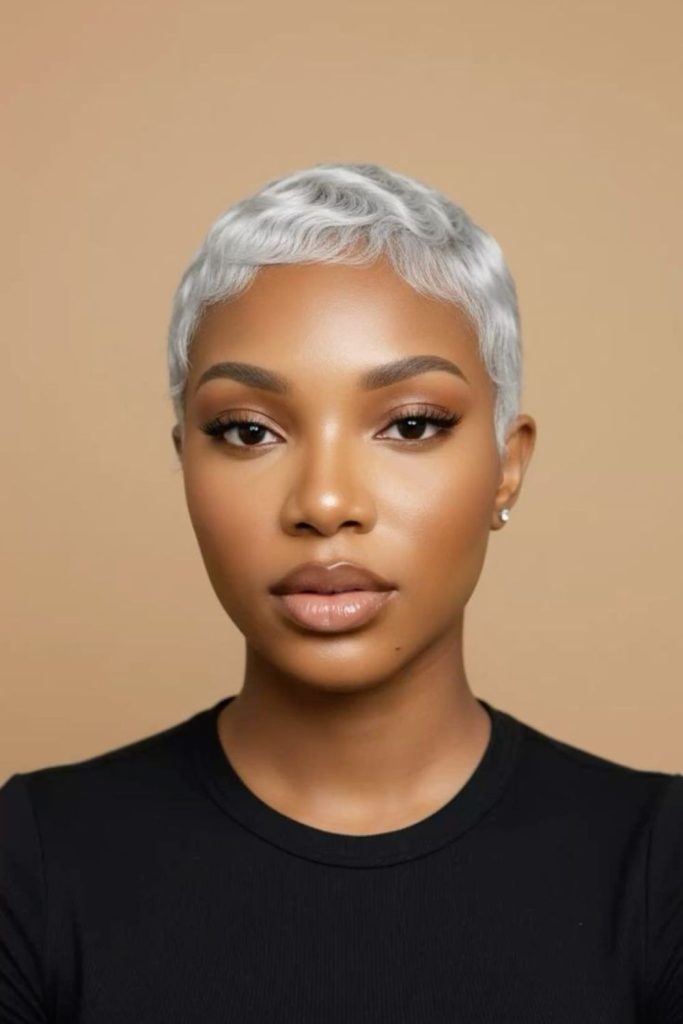Silver pixie haircut with floating layers and soft metallic movement.