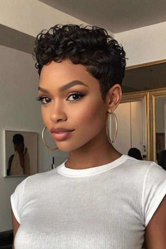Curly pixie cut with tight coils and bold voluminous structured shape.