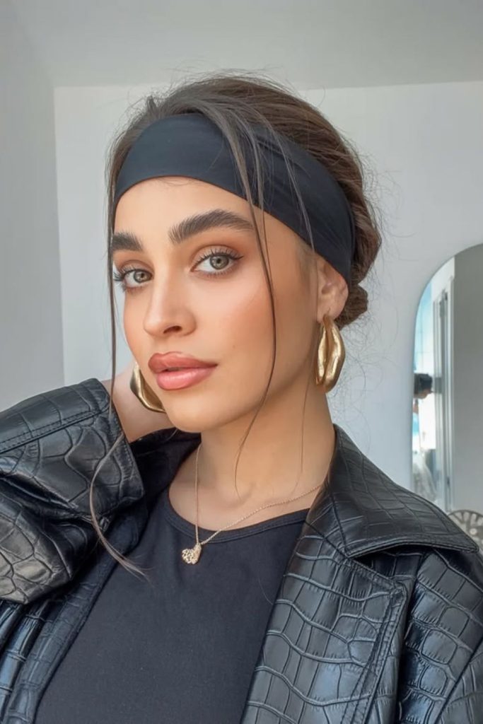Voluminous hairstyle with bold dark headband.