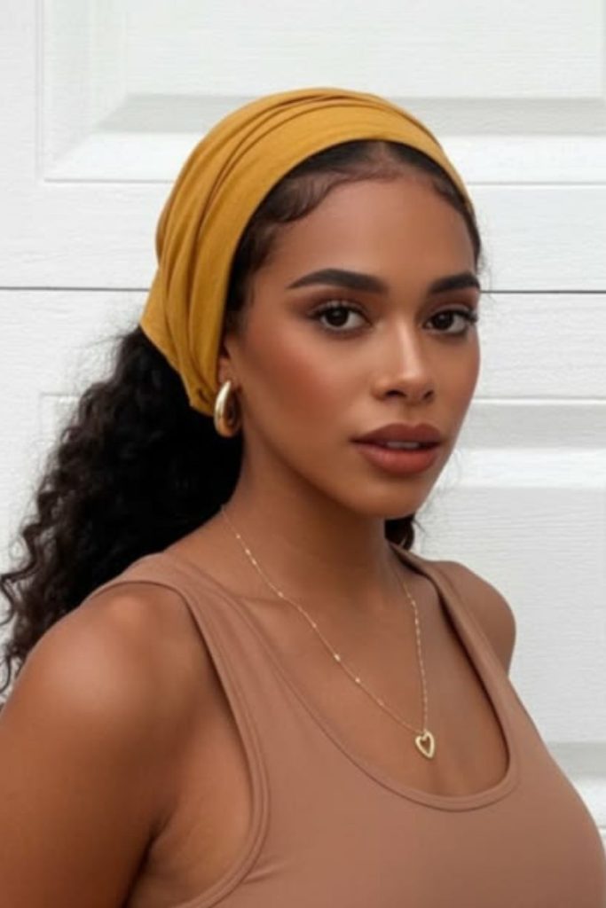 Voluminous curly hairstyle with velvet headband.