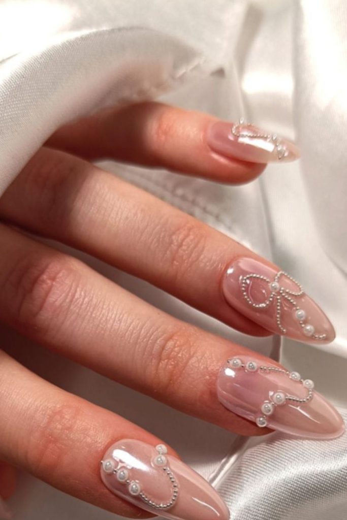 Nude pearl nails with 3D embellishments.
