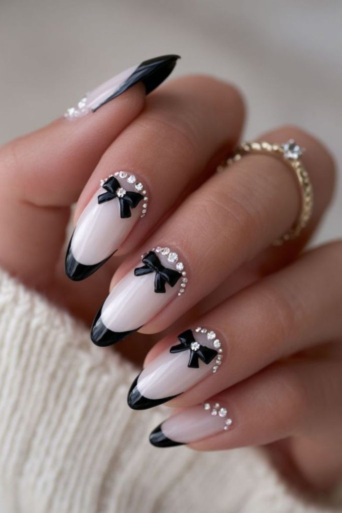 Black bow nails with rhinestone accents.