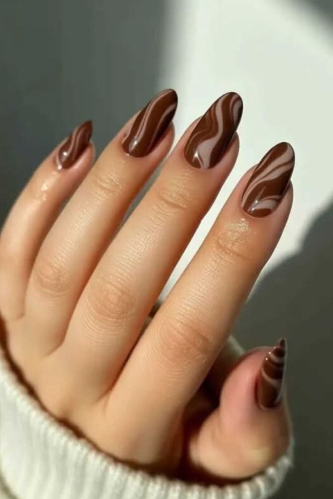 Chocolate cherry nails with glossy swirls.