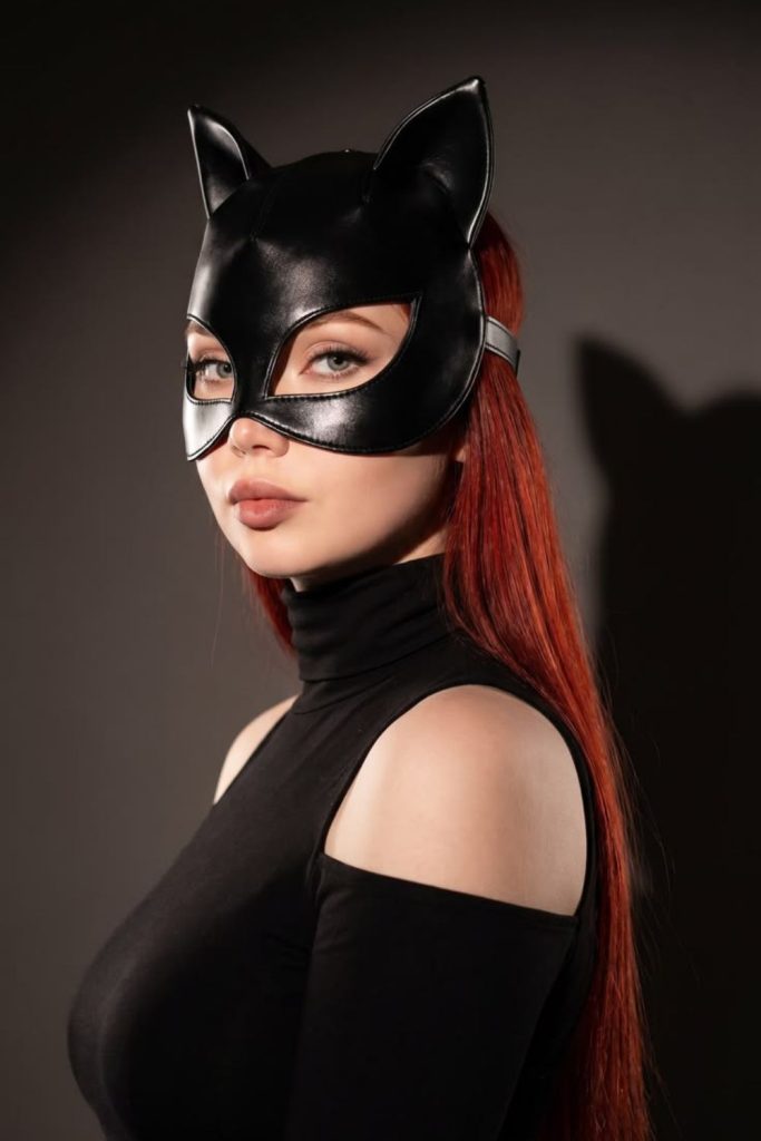Crimson-haired feline-inspired black catsuit costume.