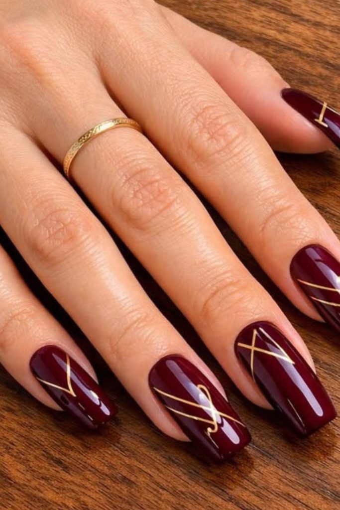 Gold-lined deep oxblood nail design.