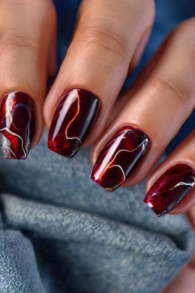 Luxurious oxblood marble vein nails.