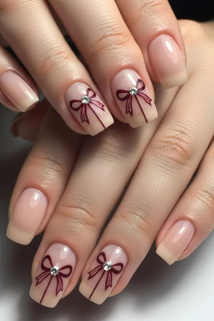 Burgundy bow nude manicure design