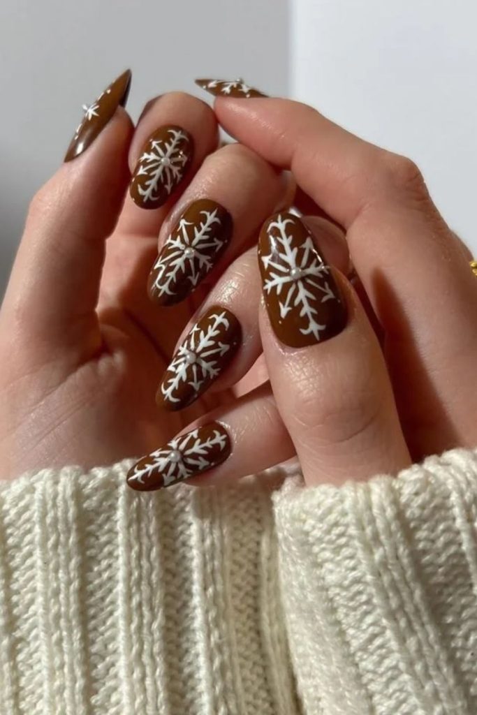 Chocolate nails with delicate white snowflakes.