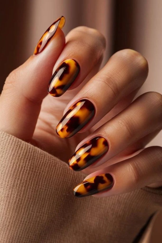 Glittery tortoiseshell nails with golden accents.