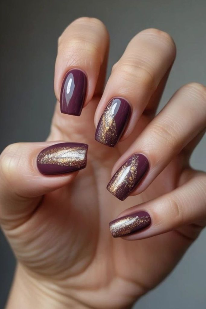 Golden accents on plum nails.