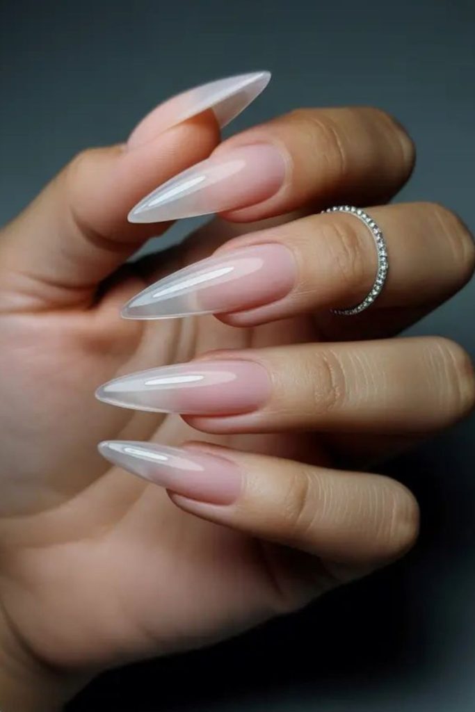 Sheer nude glossy stiletto nails.