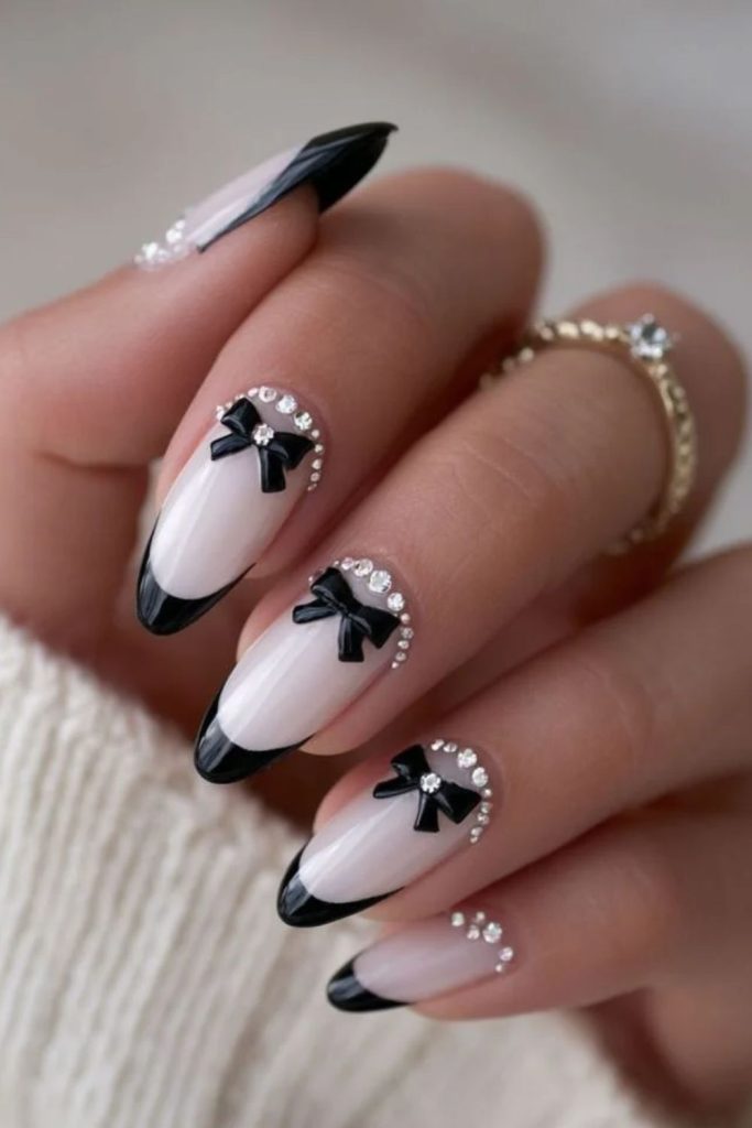 Black bow coquette nails on pale pink.