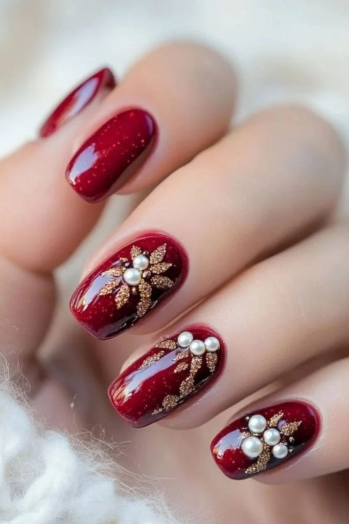 Burgundy poinsettia nail art with luxurious gold accents.