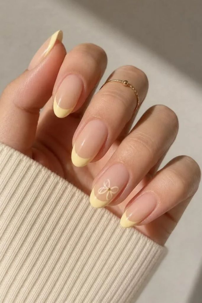 Butter yellow French tip nails with cream accents.
