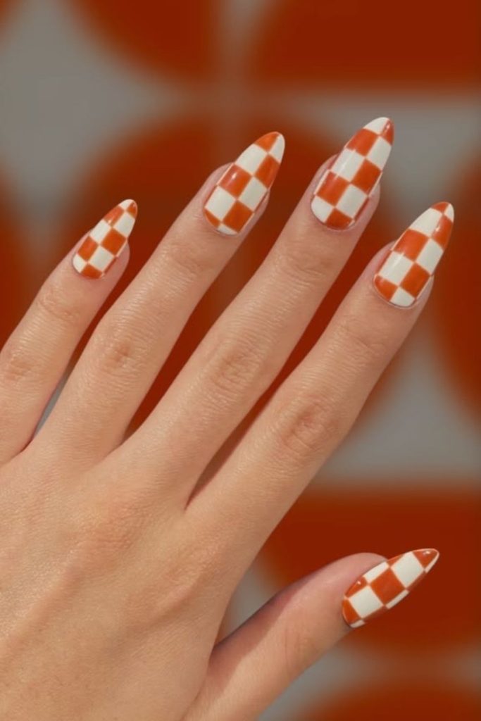 Candy corn nails featuring colorful checkerboard patterns.