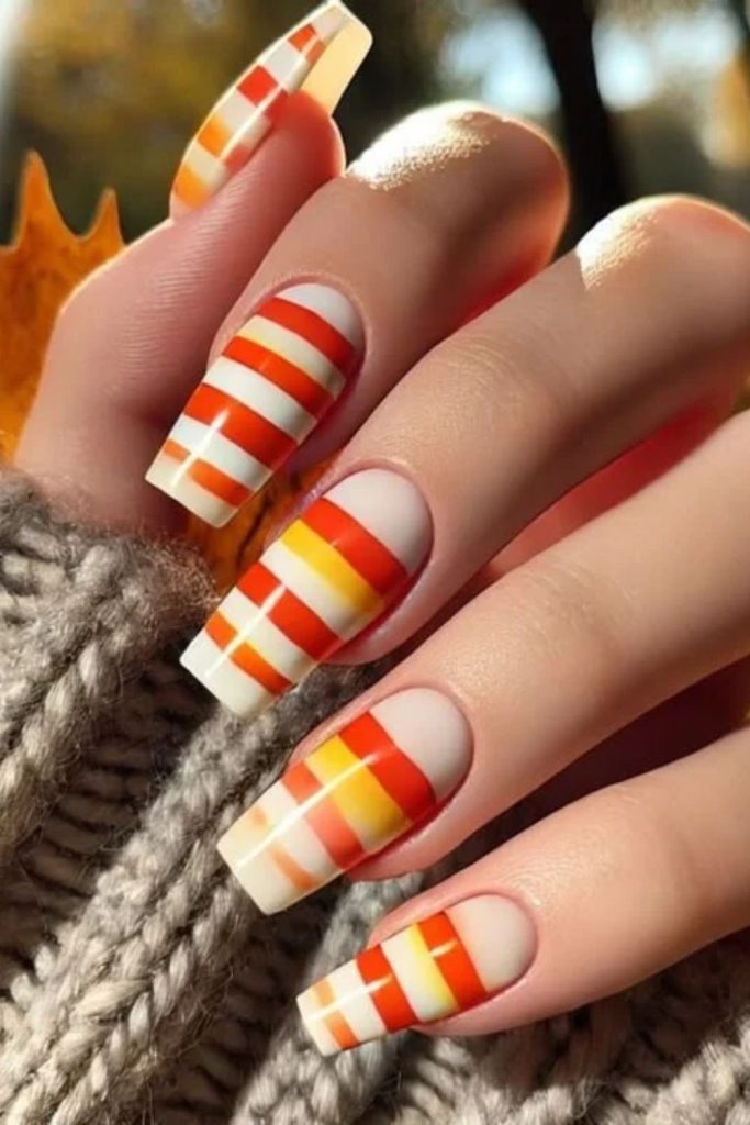 Long coffin nails with candy corn stripes.