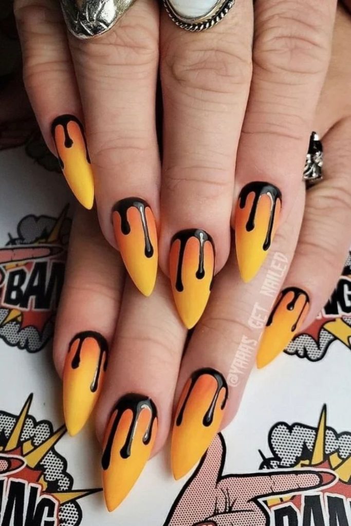 Orange candy corn nails with dripping designs.